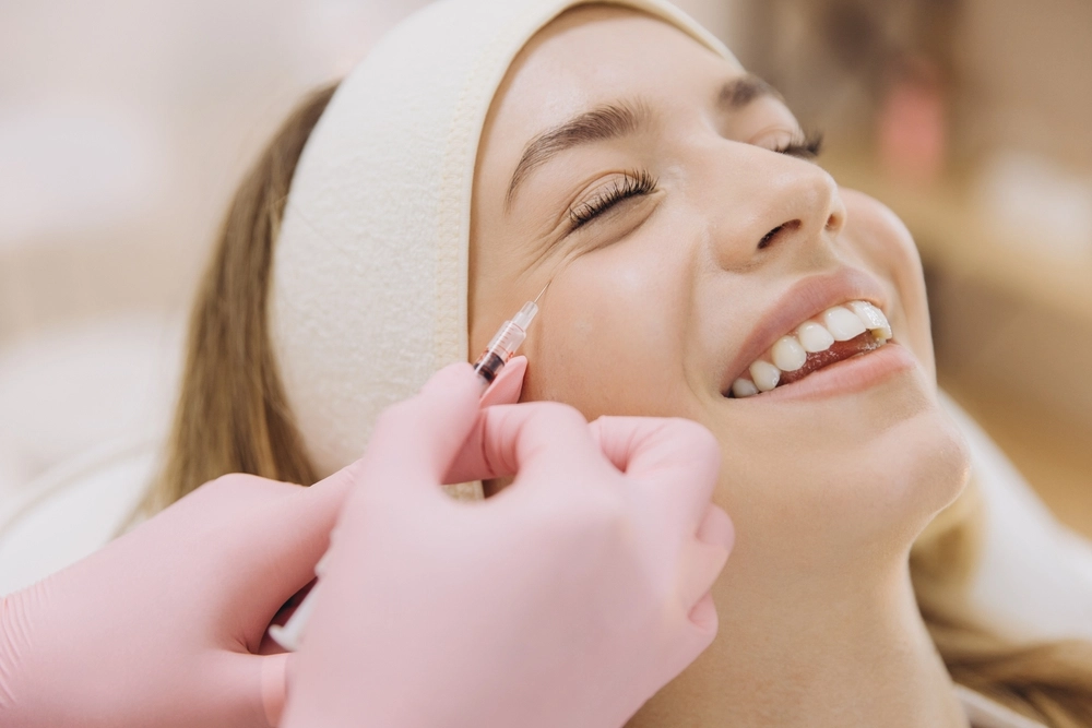 Provider in pink gloves injects filler into patient's cheek during treatment