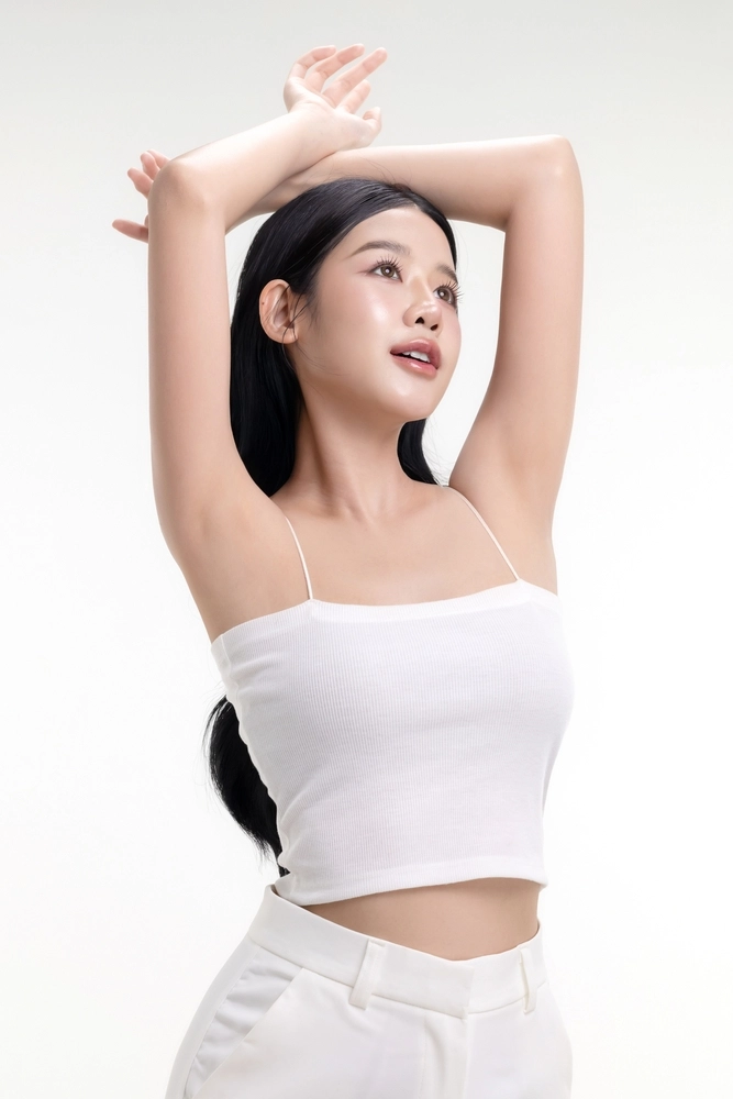 Woman with clear skin and smooth complexion posing with arms raised behind her head