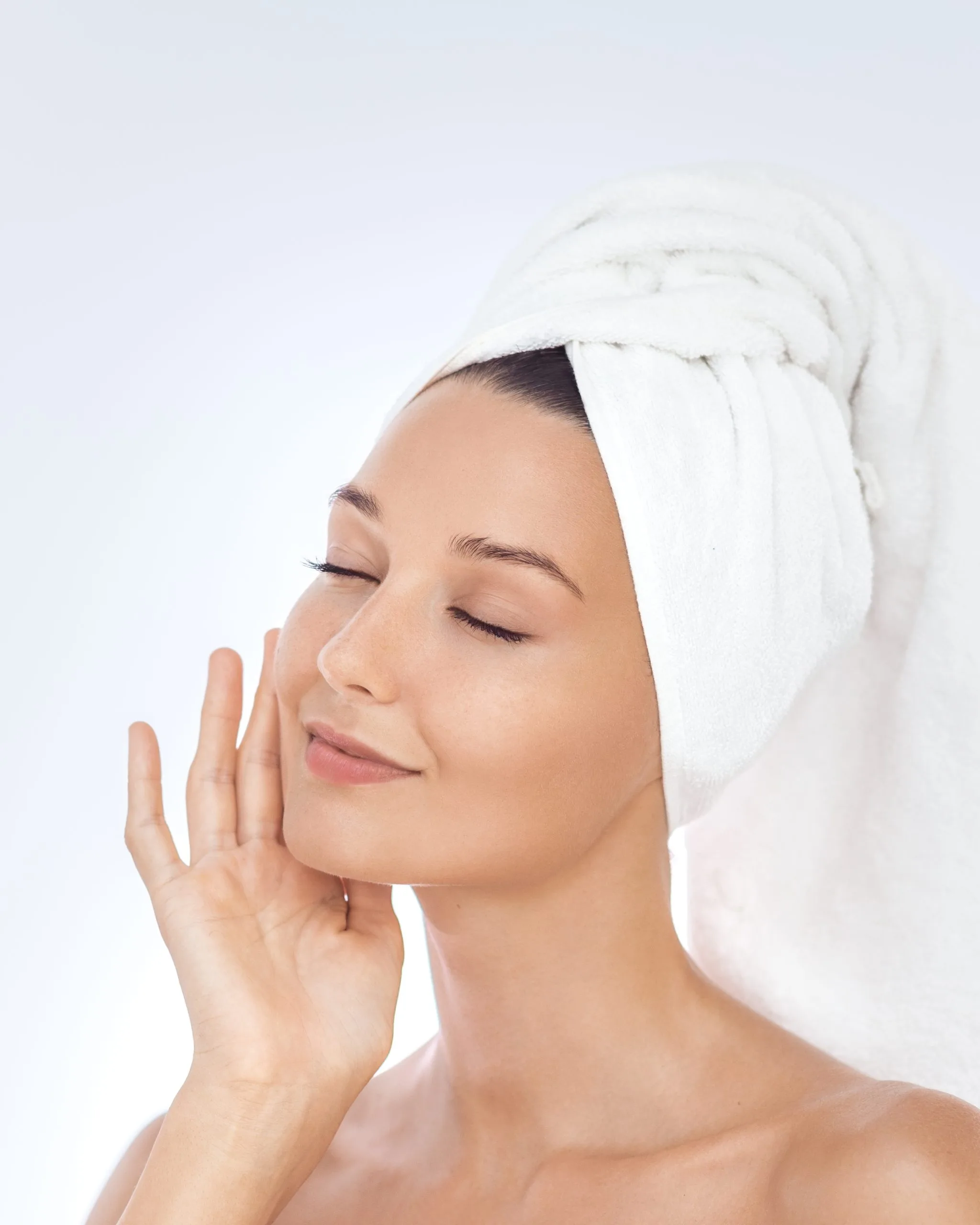 Person with white towel wrapped around head touching face with eyes closed