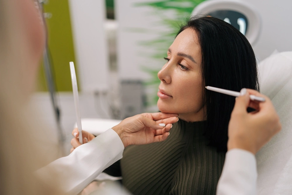 Healthcare provider examining patient's face with instrument in medical office