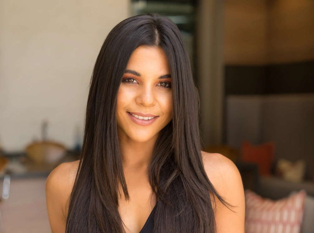 Woman smiling at camera with long black hair in indoor setting