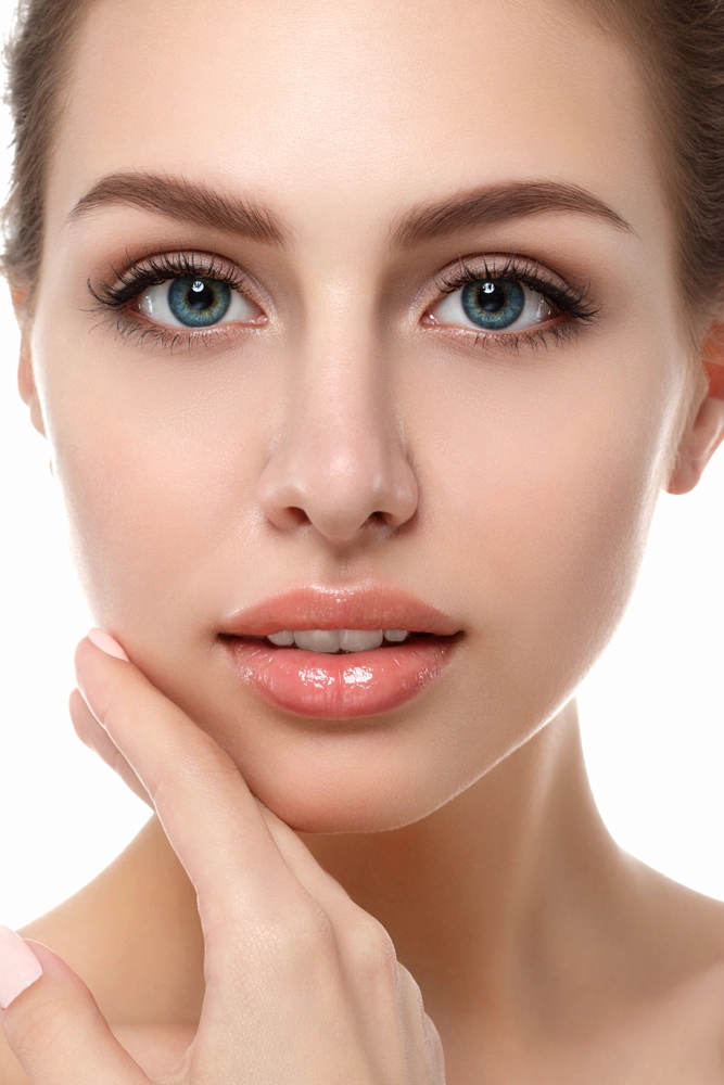 Woman with blue eyes and clear skin touching her cheek