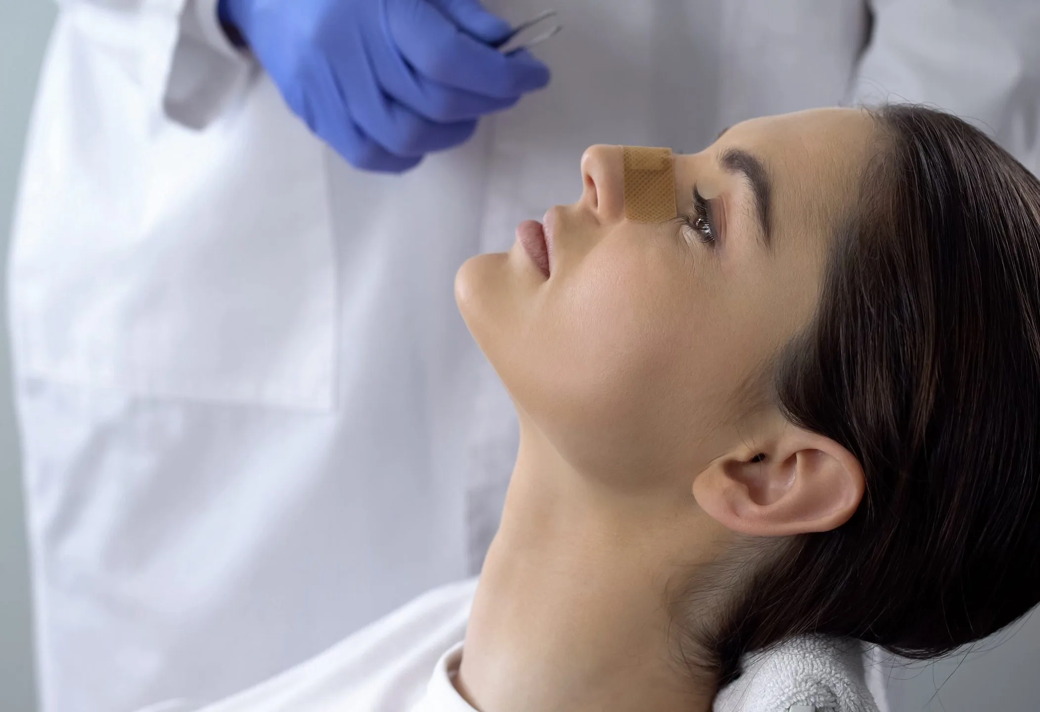 Clinician in blue gloves applying treatment to patient's face
