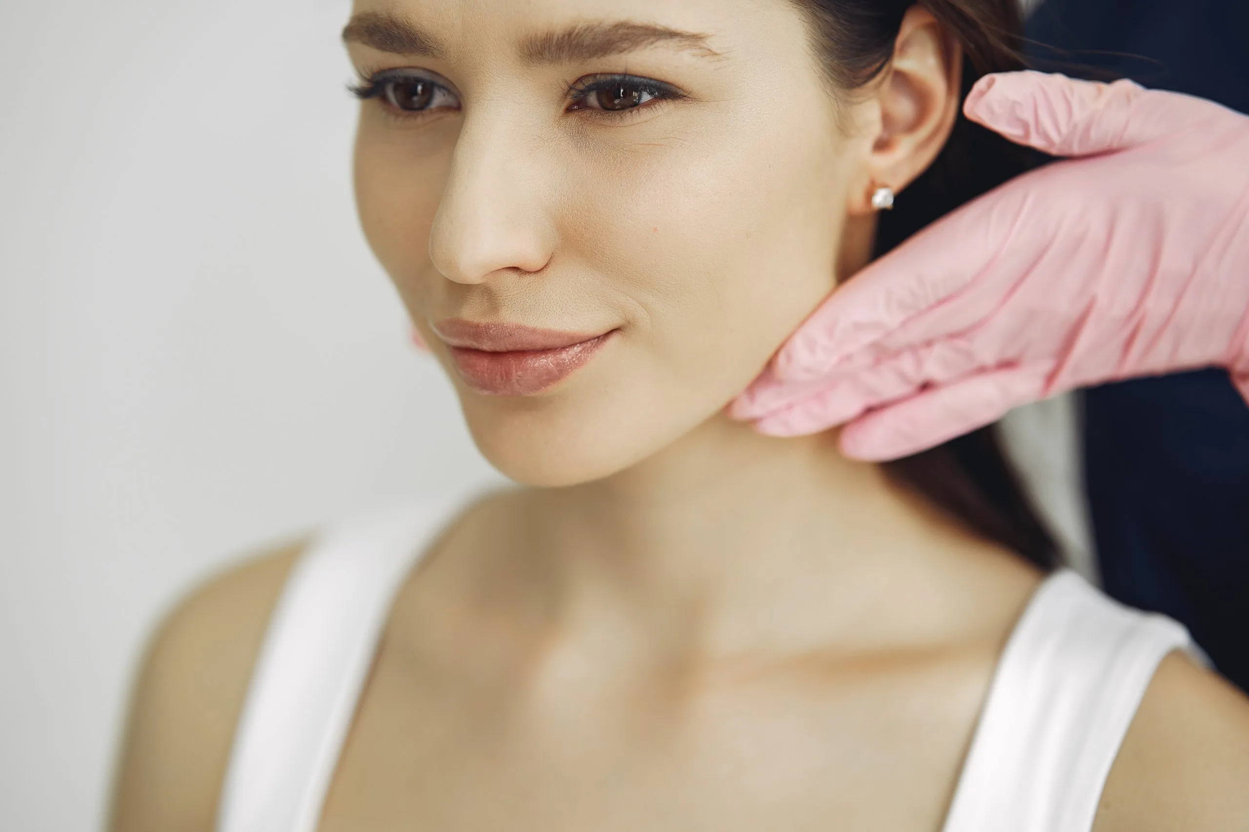 Clinician in pink gloves examining patient's face and jawline