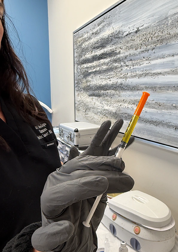 Med spa provider holding an orange and yellow syringe near injection device during weight loss treatment consultation