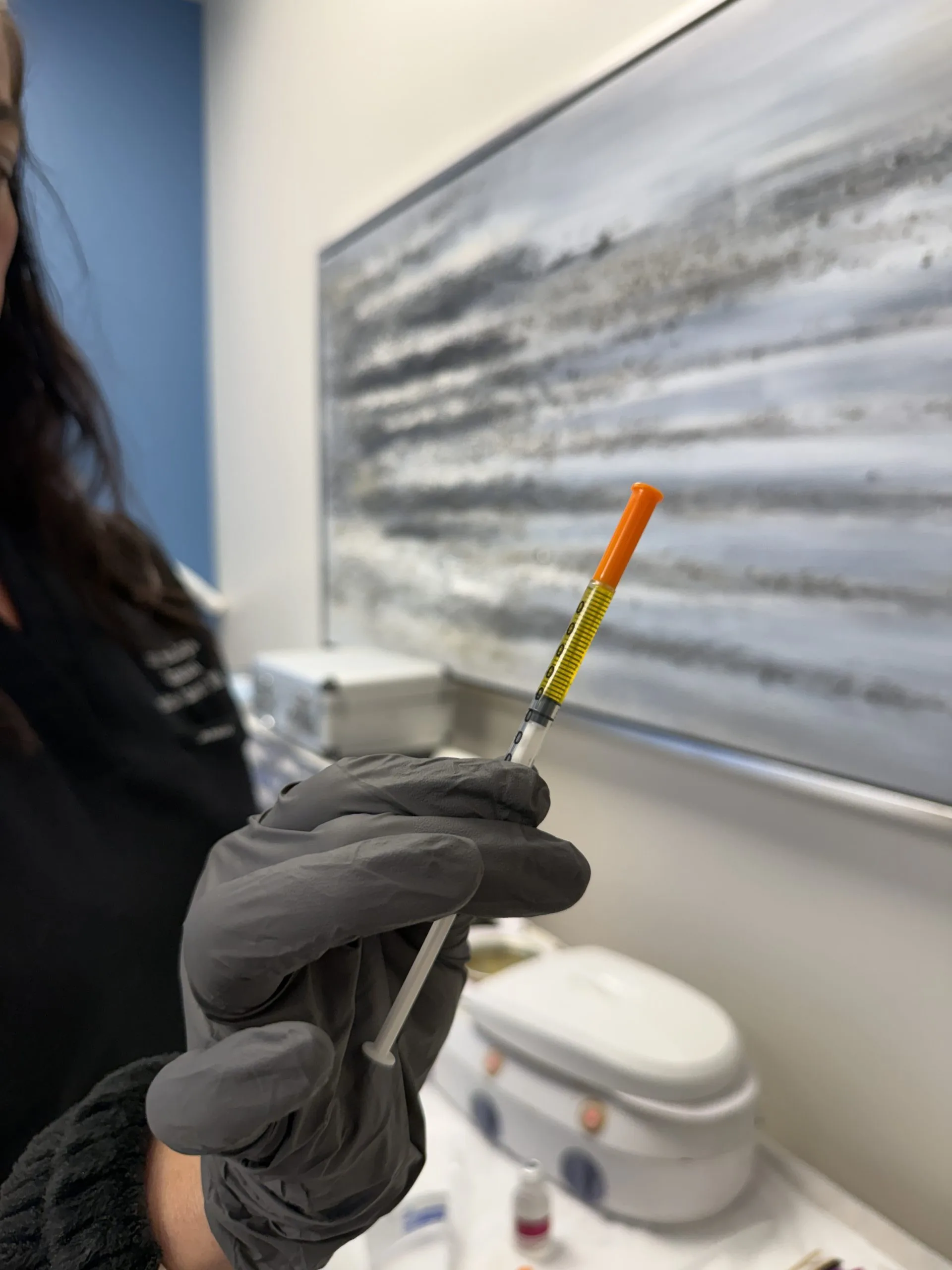 Provider holding syringe with orange plunger in clinical treatment room