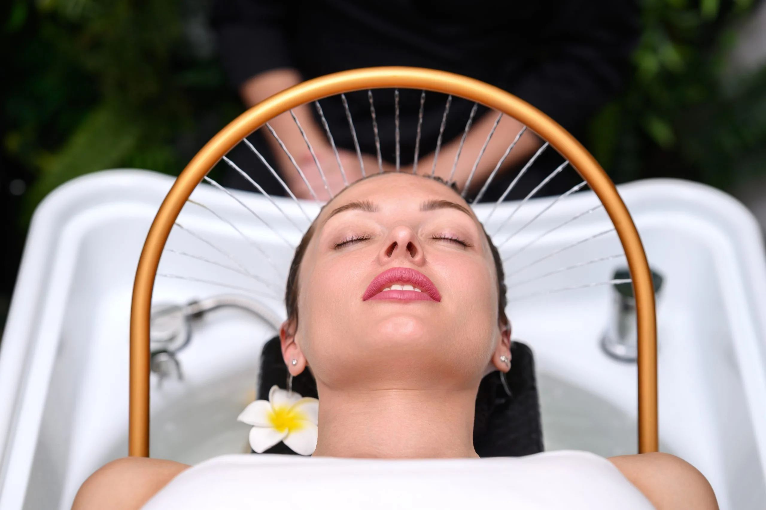 Woman relaxing in spa chair receiving light therapy treatment with golden arch device above her face