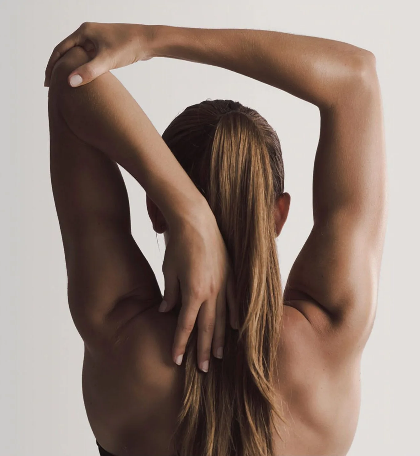 Woman stretching arms overhead showing underarm and neck