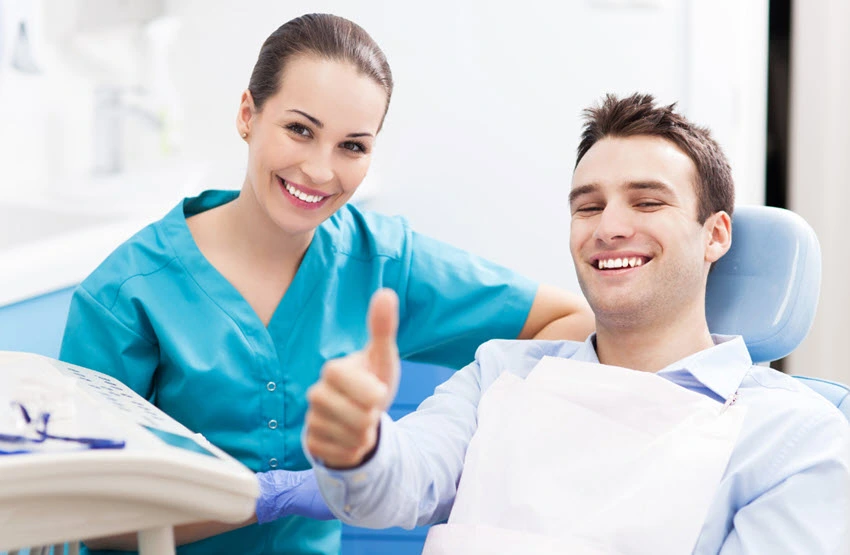 Dental hygienist and patient giving thumbs up during consultation at dental office