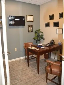 Advanced Dentistry of Collegeville consulting room with wood desk, leather chairs, dental diplomas on walls, and x-ray display monitor