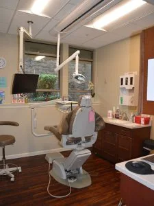 Modern dental exam room at Advanced Dentistry of Collegeville with patient chair, overhead operatory light, monitor, and treatment cabinets