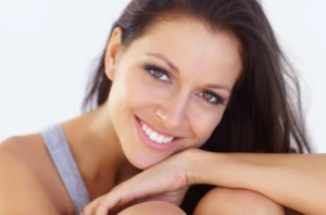 Woman with a bright white smile resting her chin on her hand