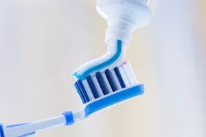 Blue toothpaste being applied to a blue and white toothbrush