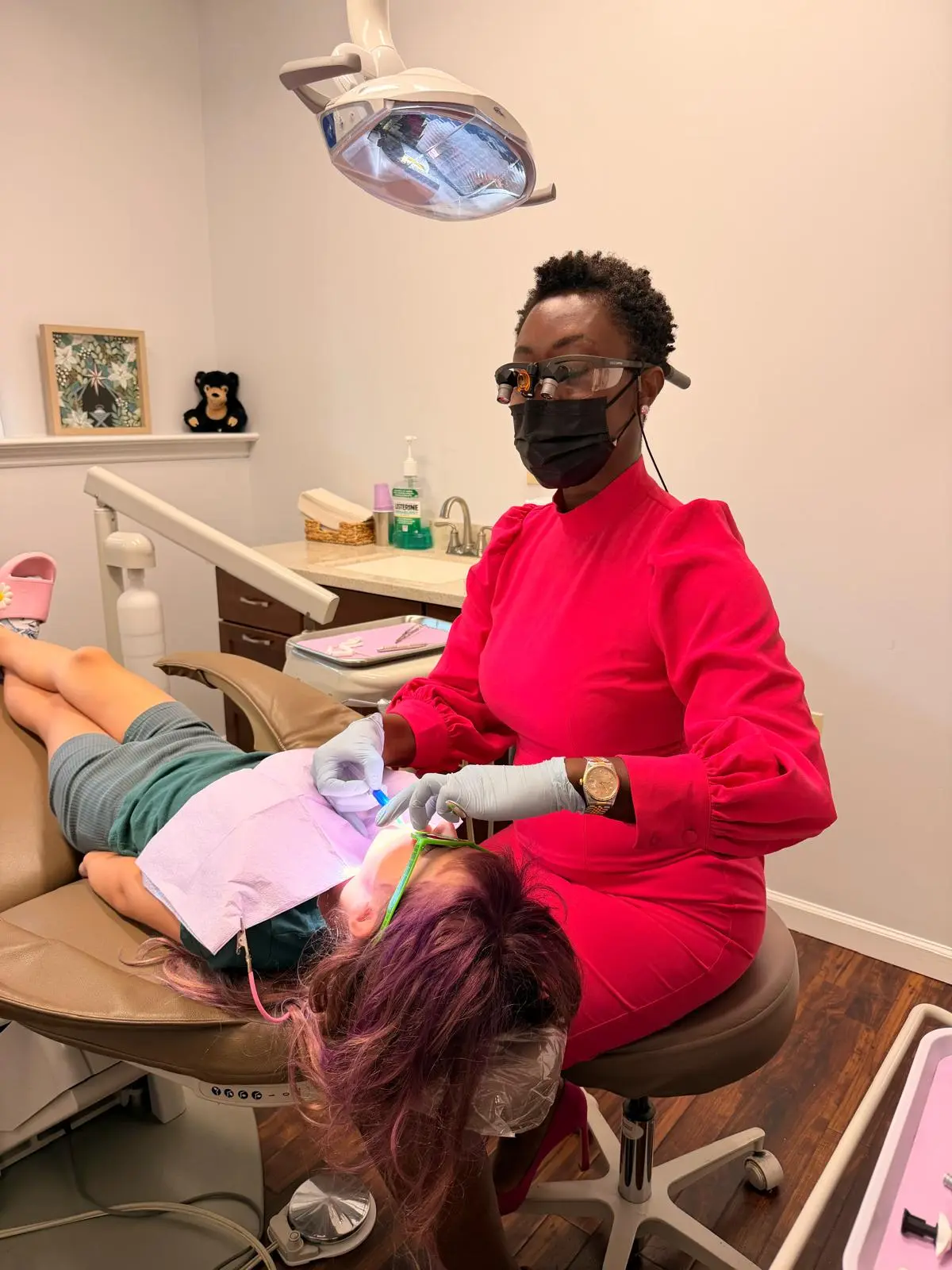 Dr. Nelly Silva treating a relaxed, reclined patient while a team member holds the patient's hand in a Collegeville treatment room