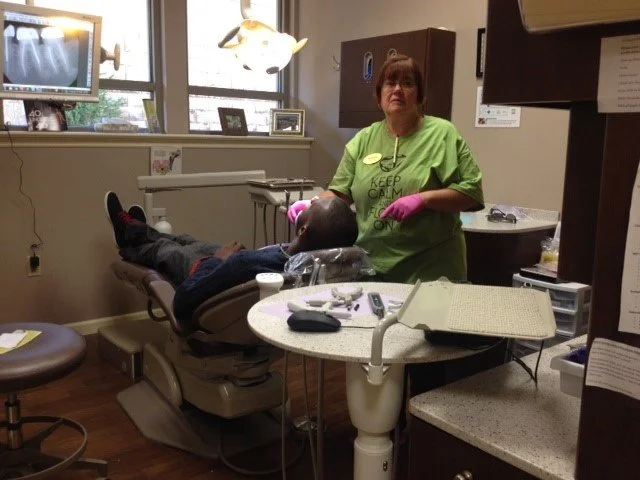 Team member in green scrubs and pink gloves treating a patient in the dental chair at Advanced Dentistry of Collegeville