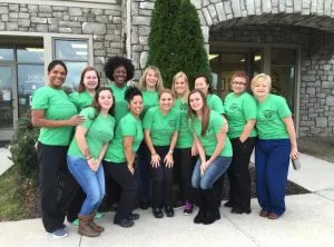 Advanced Dentistry of Collegeville team in green shirts posing outside the Main Office entrance