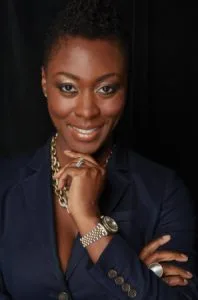 Woman in dark blazer smiling at camera against black background