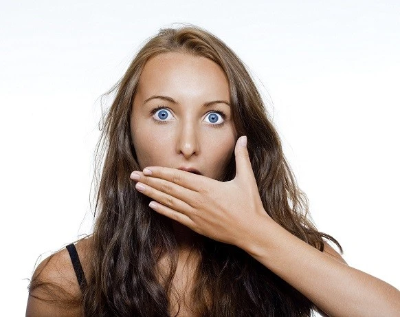 Woman with hand over mouth expressing concern about bad breath
