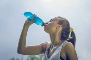 Woman drinking water from a blue bottle outdoors