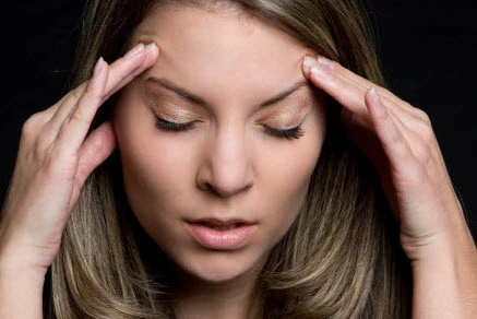 Woman holding her head with both hands, eyes closed, expressing stress and tension
