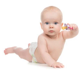 Infant holding a colorful teething toy while crawling