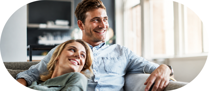 Couple sitting together on couch looking upward with warm smiles