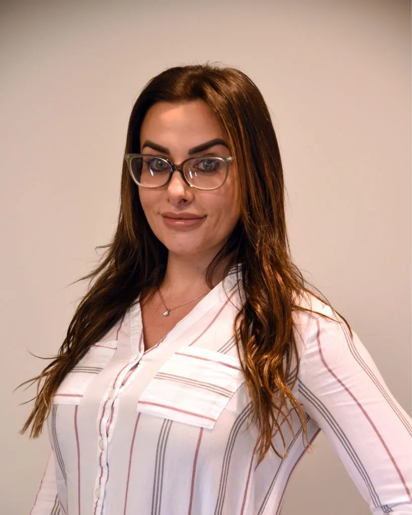 Amy Adely professional headshot wearing glasses and pink striped shirt
