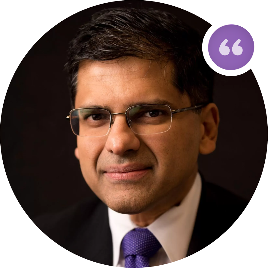 Professional headshot of male dentist wearing glasses and purple tie