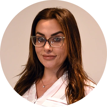 Professional headshot of woman with brown hair and glasses wearing pink top
