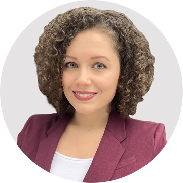 Woman with curly brown hair wearing maroon blazer smiling at camera