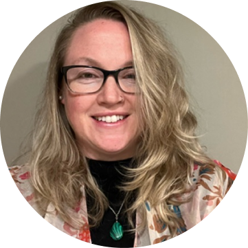 Haley Mozonski, team member, smiling at camera wearing glasses and patterned jacket
