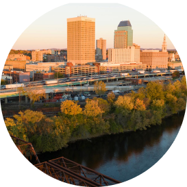 Downtown skyline with orange and gold buildings along river with autumn foliage