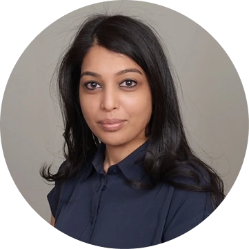 Woman with long dark hair wearing a dark blue collared shirt, portrait against neutral background