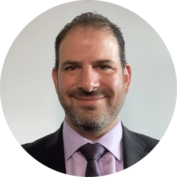 Professional headshot of male team member with beard wearing purple tie