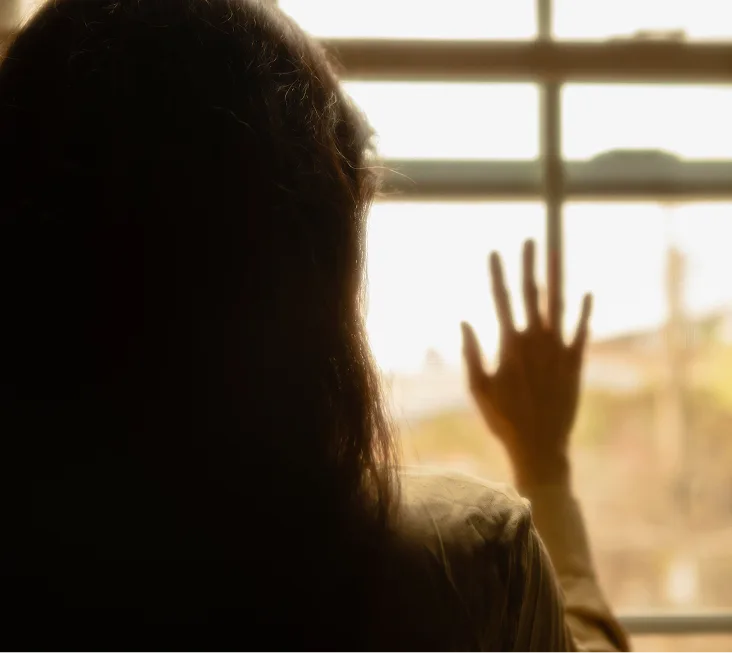 Person at a sunny window reaching toward the light