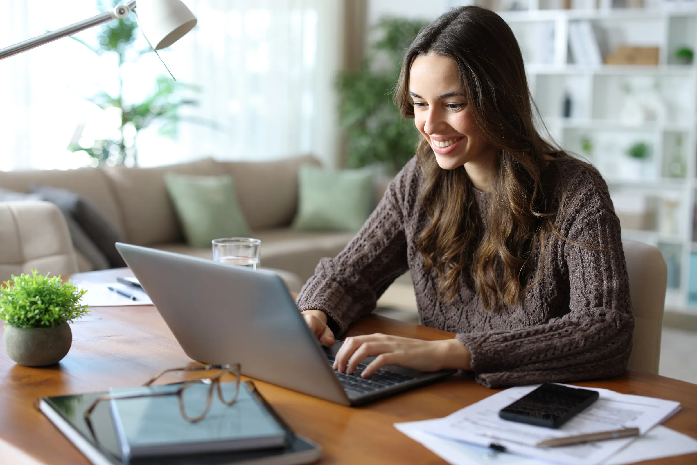 Woman smiling while typing on her laptop at home