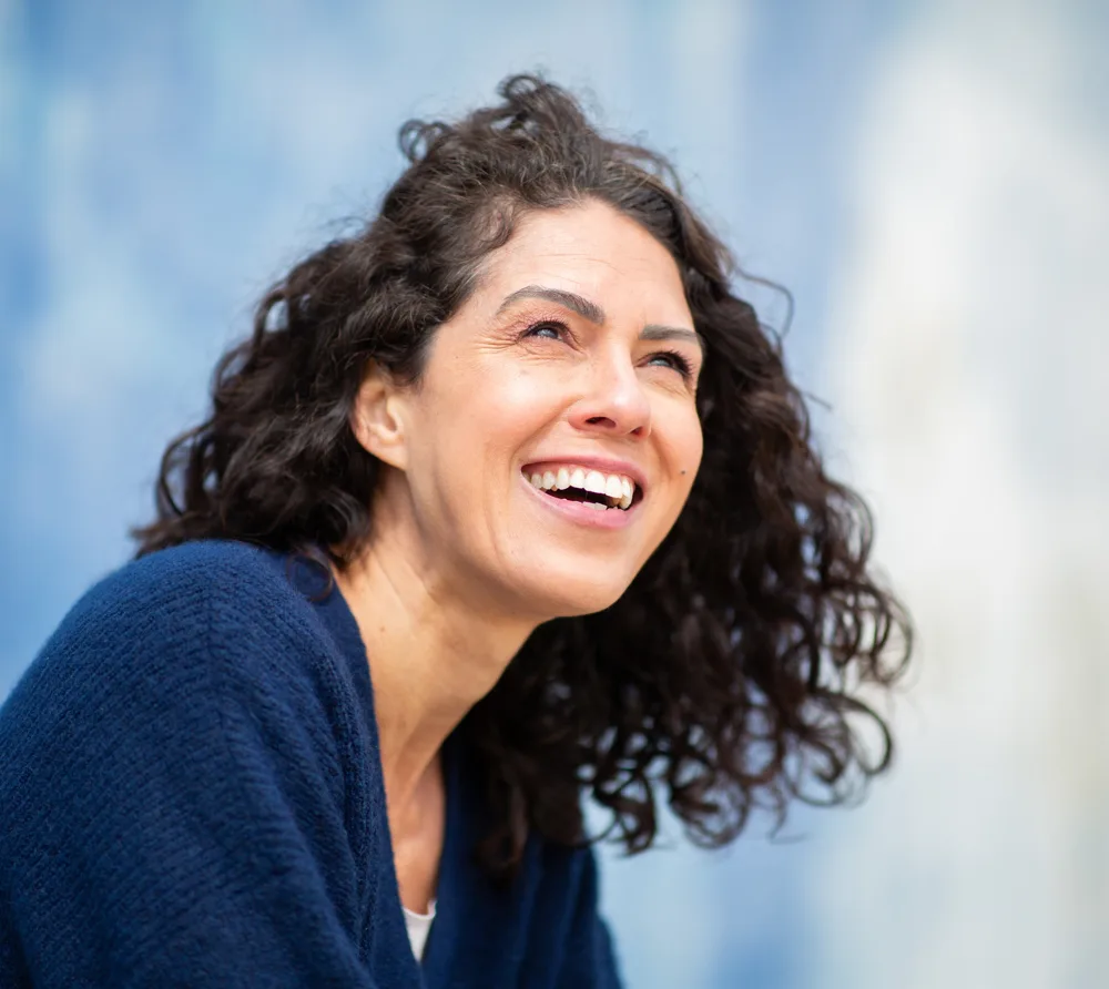Woman with curly hair smiling and looking upward
