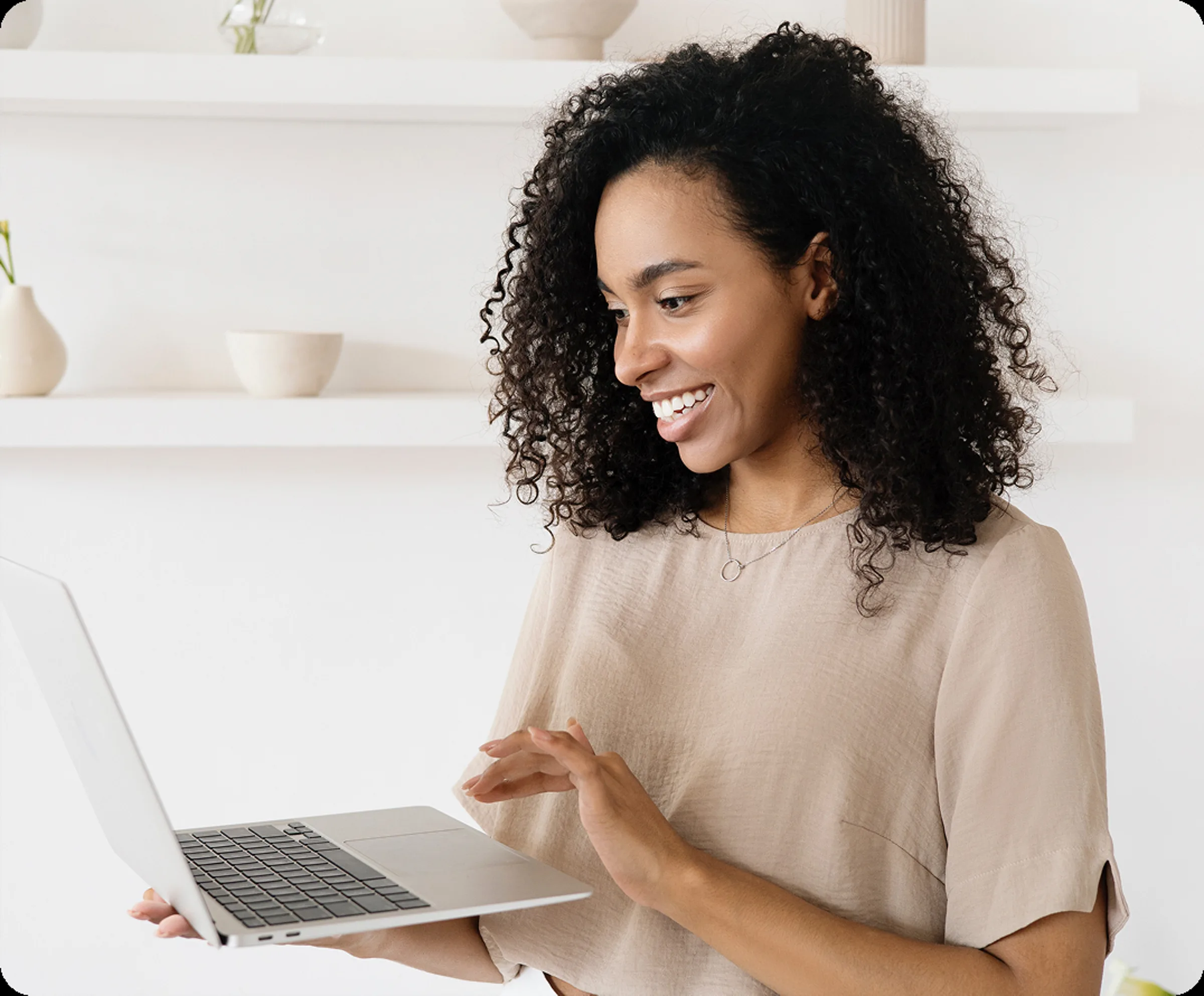Woman with curly hair holding a laptop during a video visit