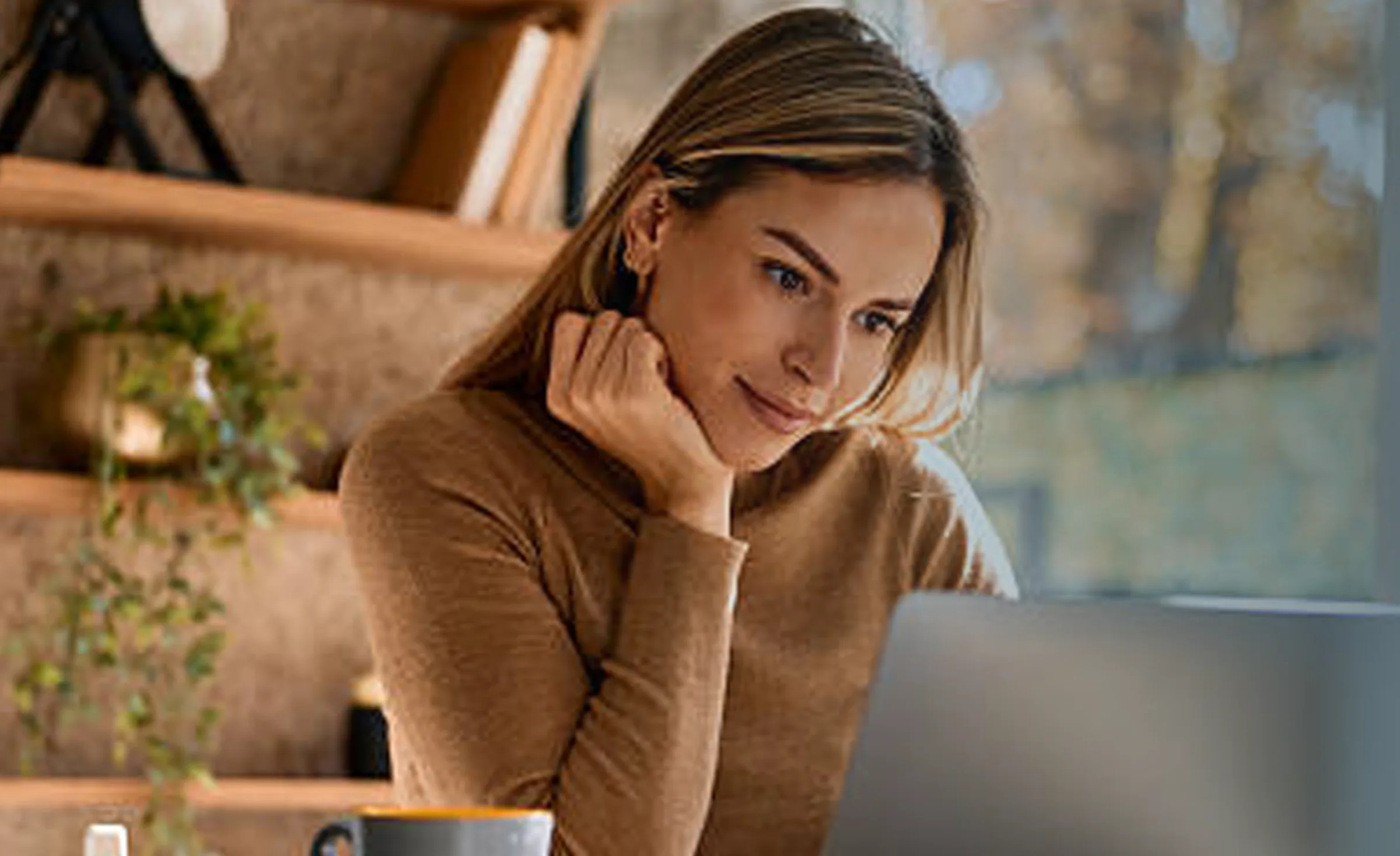 Woman smiling at her laptop in a cozy home office