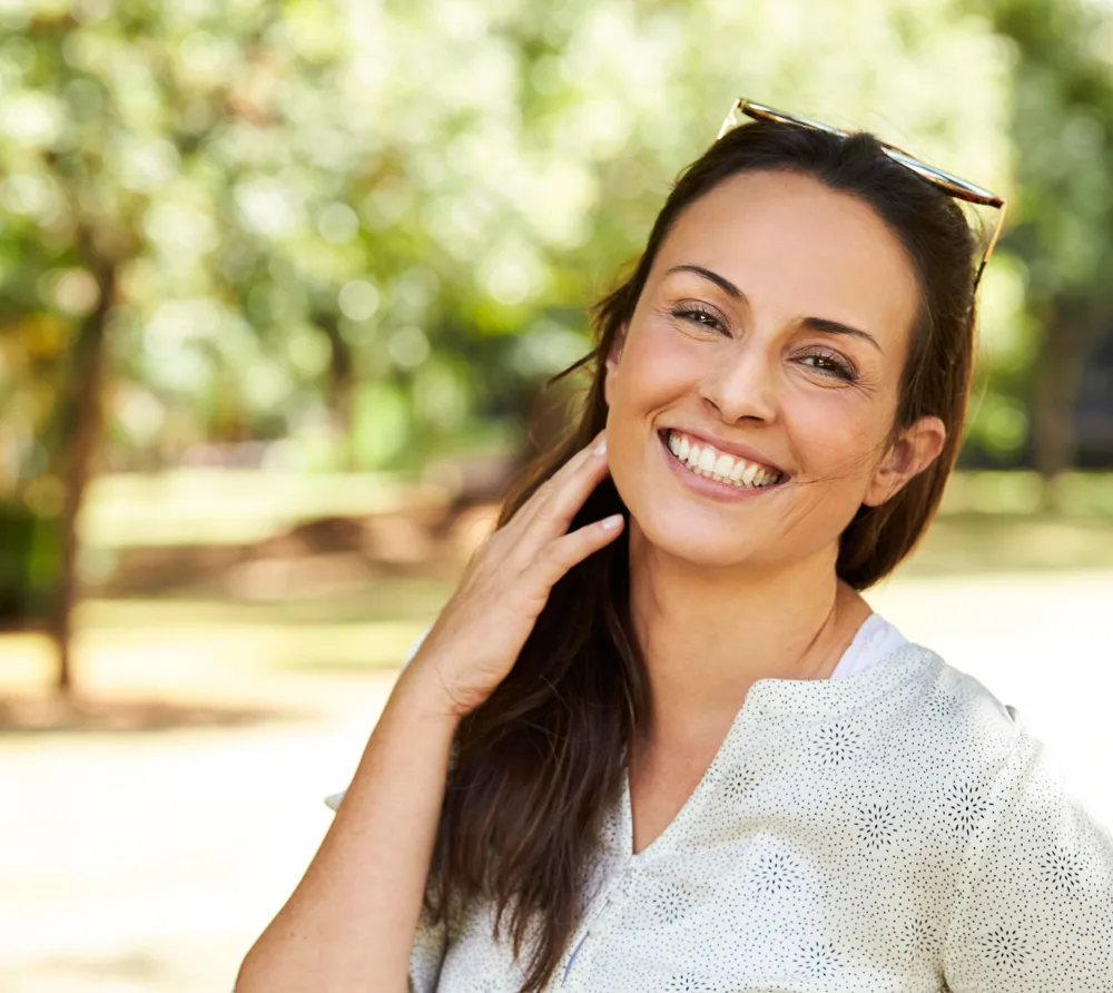 Smiling woman standing in a sunlit park