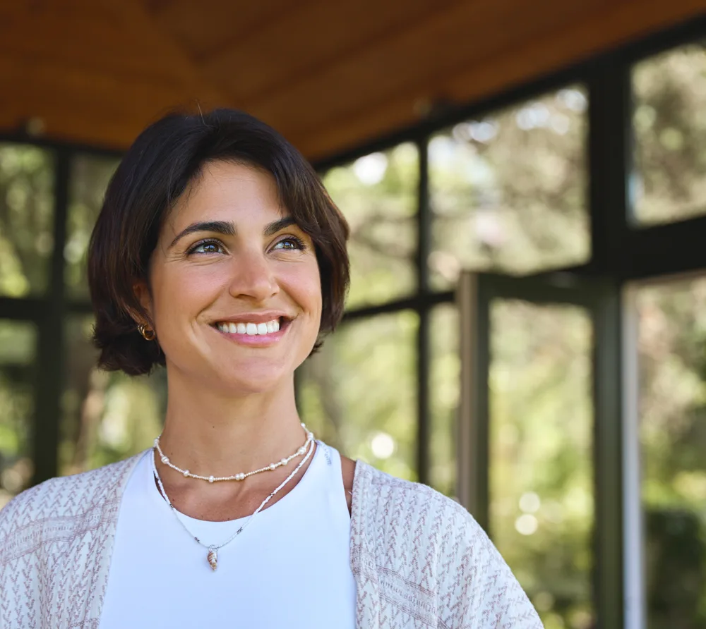 Smiling woman outdoors under a wooden pergola