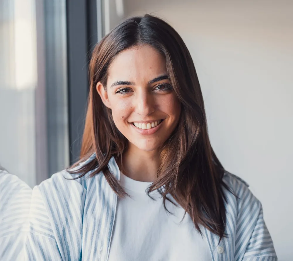 Smiling woman with long brown hair by a window