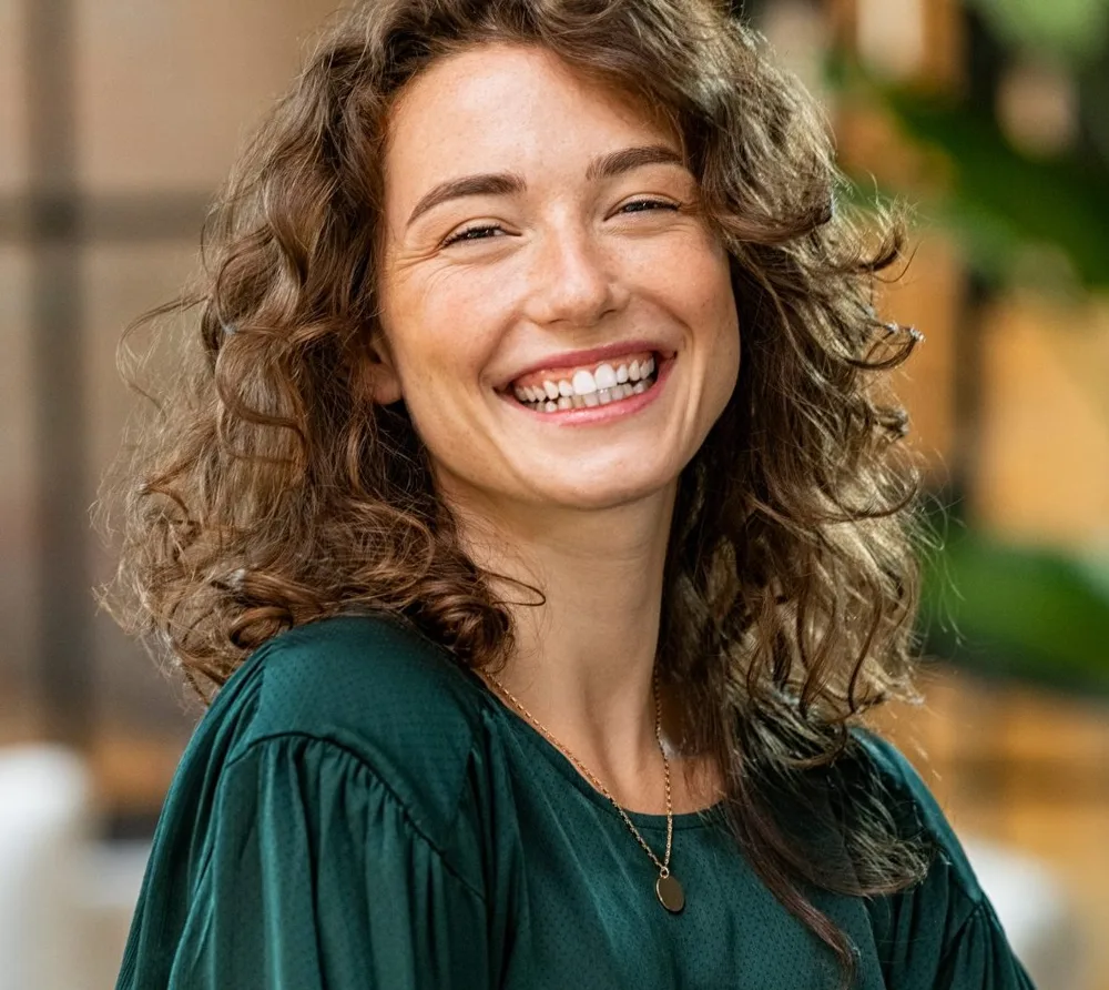 Smiling woman with curly hair, arms crossed