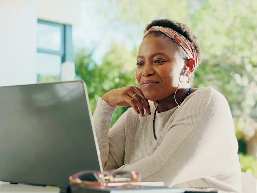 Woman with earphones smiling during a video visit at her laptop