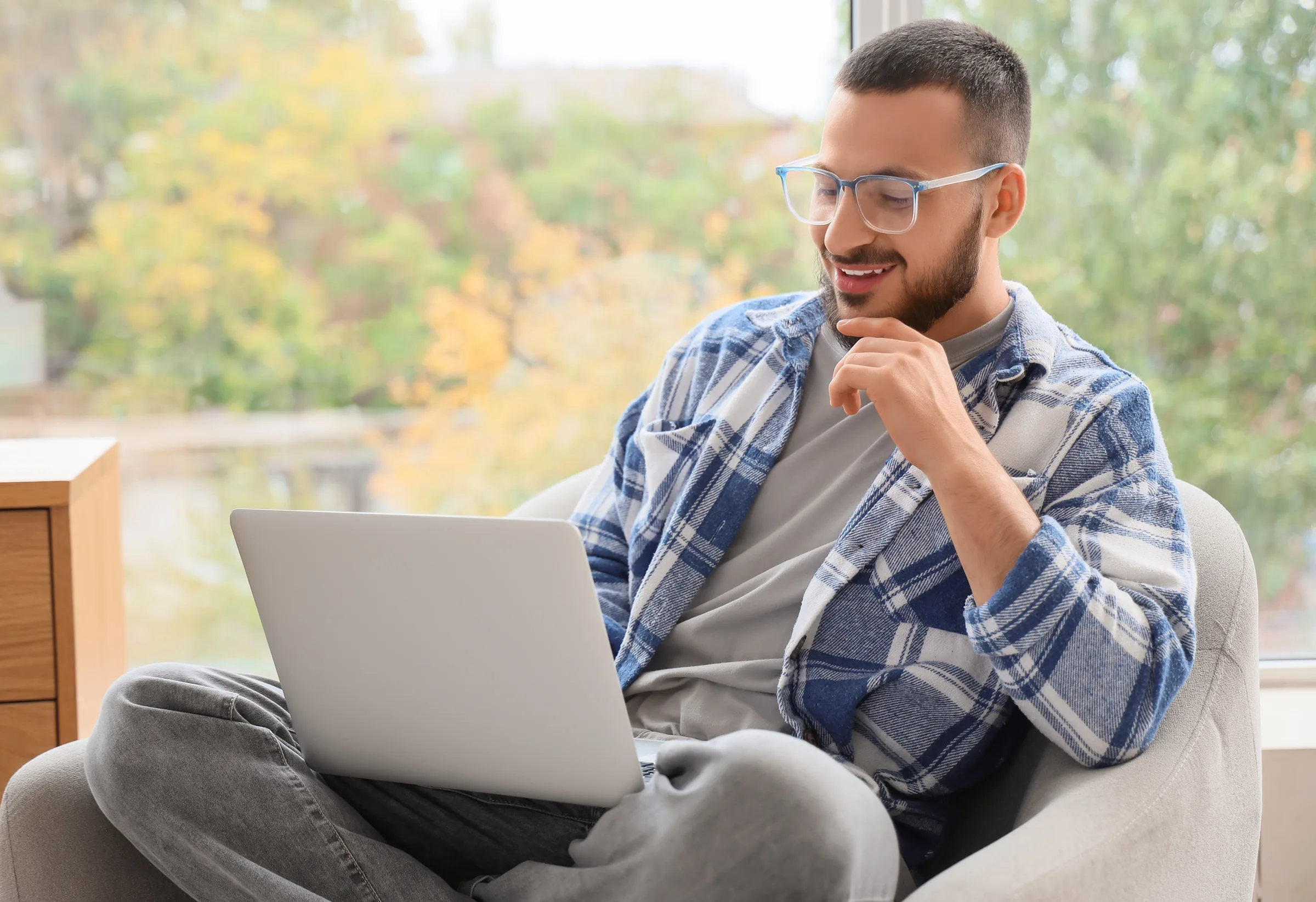 Man in an armchair joining a video visit on his laptop