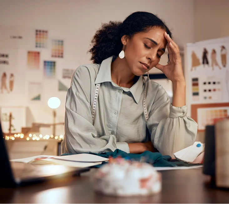 Stressed woman with her hand on her forehead at a desk