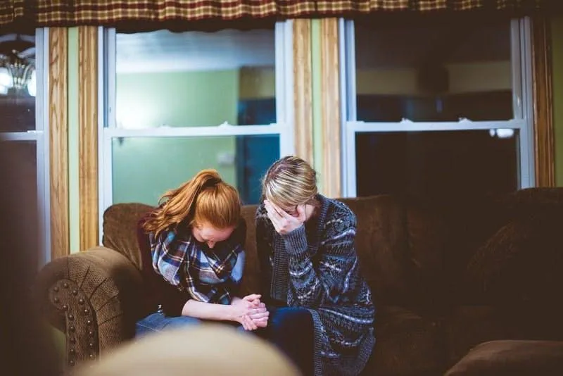Therapist sitting with young patient on couch during counseling session by window