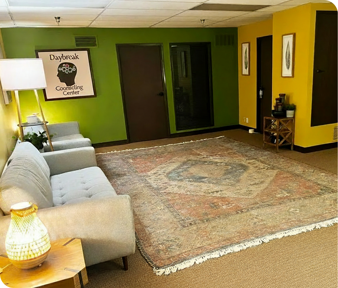 Daybreak Counseling Center Cerritos waiting room with cream seating, green and yellow walls, Daybreak Correcting Center logo sign, and neutral-toned rug
