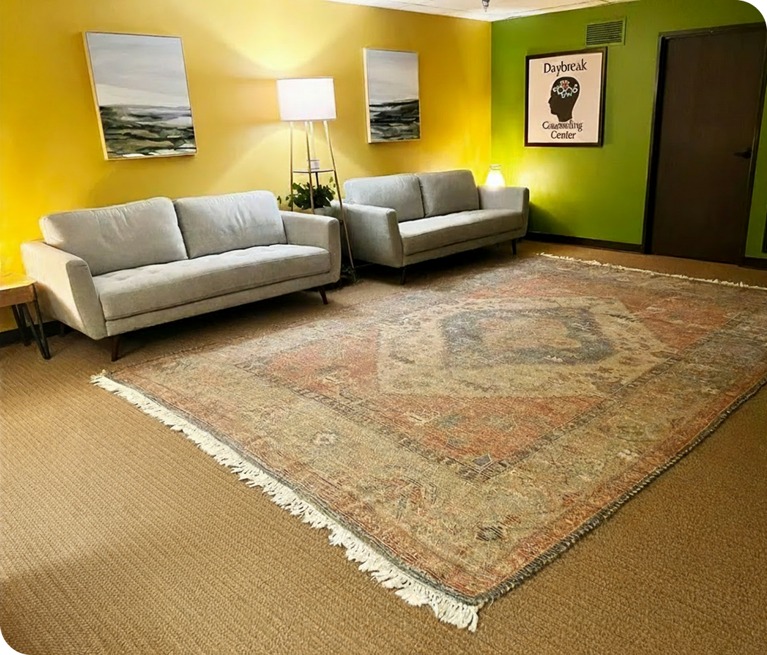 Daybreak Counseling Center Cerritos waiting room with yellow and green walls, two gray couches, and ocean landscape artwork