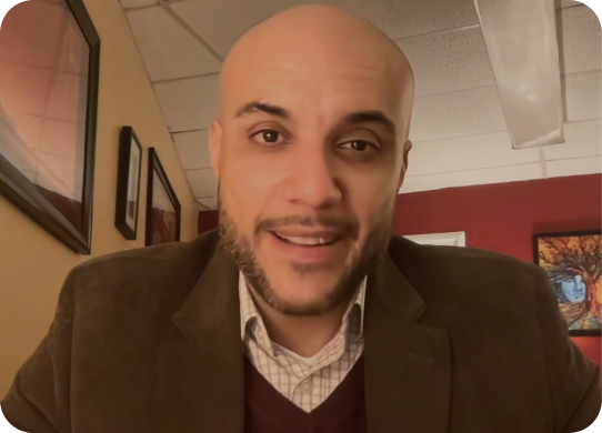 Man in brown blazer smiling at camera in counseling office